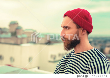 Peaceful young man in red hat thinking while looking into the distance Peaceful young man in red hat thinking while looking into the distance 44277774