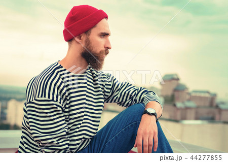 Calm bearded man sitting on the roof and looking into the distance Calm bearded man sitting on the roof and looking into the distance 44277855