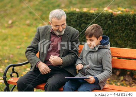 Grandson explains his grandfather how to use tablet. Child help older generation 44281240