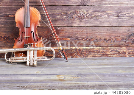 Aged violin and trumpet on wooden background. 44285080