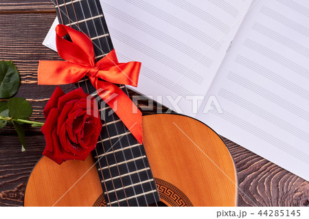 Guitar and musical notes on wooden background. 44285145