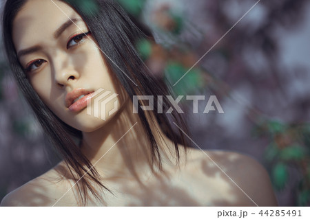 Beautiful girl standing at blossoming tree in the garden 44285491