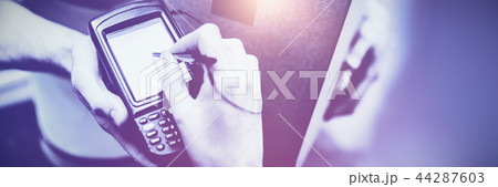Woman signing on device to delivery parcel Woman signing on device to delivery parcel 44287603