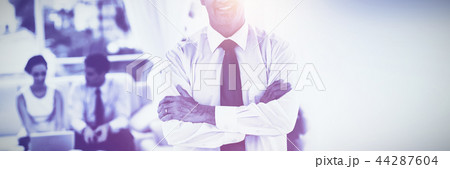 Executive posing while his colleagues are working Executive posing while his colleagues are working 44287604