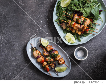 Chicken on skewers on oval dish and fresh salad  44296465