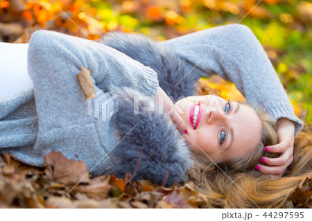 Beautiful young happy woman lying in autumn park Beautiful young happy woman lying in autumn park 44297595