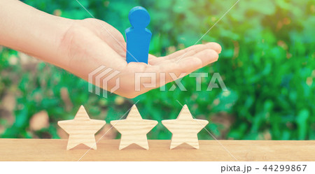 The hand holds a human figure and three stars The hand holds a human figure and three stars 44299867
