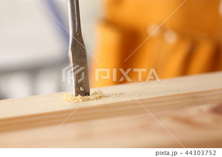 Flat drill bit make hole in wooden bar closeup Flat drill bit make hole in wooden bar closeup 44303752