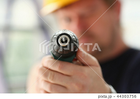 Arms of worker using electric drill closeup Arms of worker using electric drill closeup 44303756