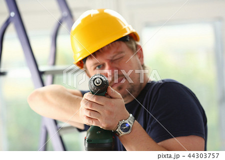 Arms of worker using electric drill closeup Arms of worker using electric drill closeup 44303757
