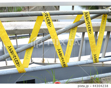 立入禁止テープの張られた破損した橋の手すりの写真素材
