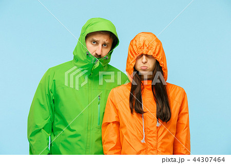 The young couplel posing at studio in autumn jackets isolated on blue The young couplel posing at studio in autumn jackets isolated on blue 44307464