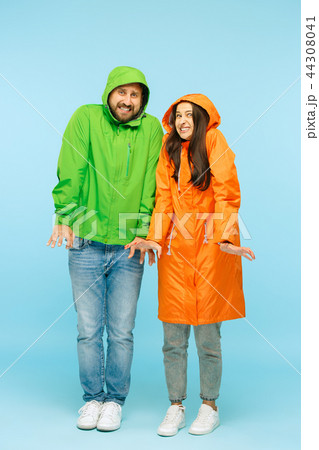 The young couplel posing at studio in autumn jackets isolated on blue 44308041