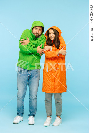 The young couplel posing at studio in autumn jackets isolated on blue 44308042