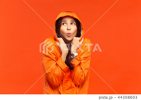 The young girl posing at studio in autumn jacket isolated on red 44308603