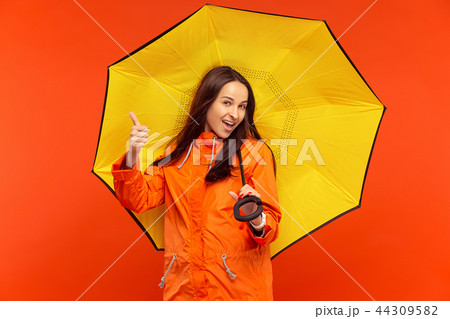 The young girl posing at studio in autumn jacket isolated on red 44309582