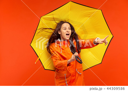 The young girl posing at studio in autumn jacket isolated on red The young girl posing at studio in autumn jacket isolated on red 44309586