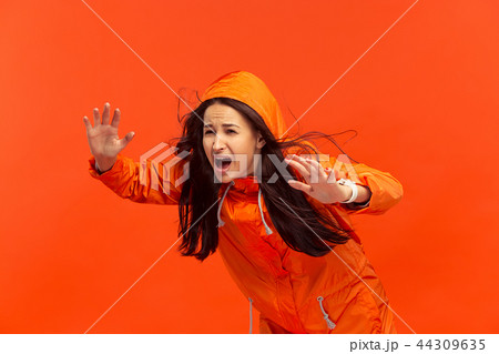 The young girl posing at studio in autumn jacket isolated on red 44309635