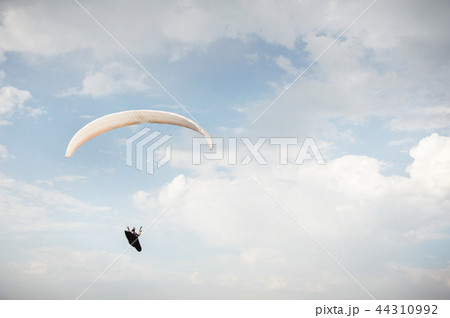 Alone paraglider flying in the blue sky against the background of clouds. Paragliding in the sky on 44310992