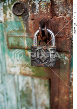 Old metallic padlock on wood,I have not painted the gate. Green shabby paint. Old metallic padlock on wood,I have not painted the gate. Green shabby paint. 44310997