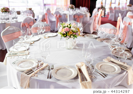 Round table at a luxury wedding reception. Beautiful flowers on the table. Serving dishes, glass 44314297