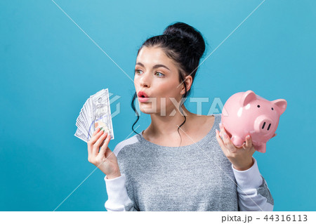 Young woman with a piggy bank with us dollar bills Young woman with a piggy bank with us dollar bills 44316113