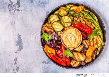Grilled vegetables on a plate with sauce. 44330962