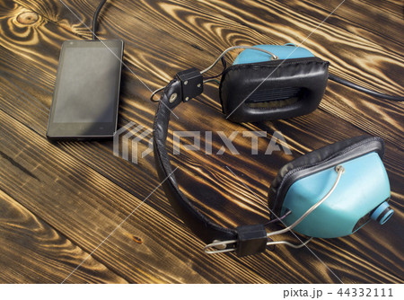 Old audio headphones and modern phone, wooden background Old audio headphones and modern phone, wooden background 44332111