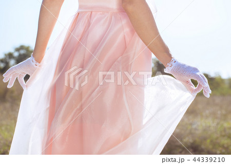 The hands in white gloves are holding a dress 44339210
