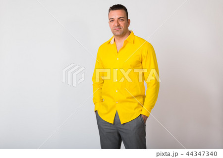 Portrait Of Man Wearing Yellow Shirt Against White Background Portrait Of Man Wearing Yellow Shirt Against White Background 44347340