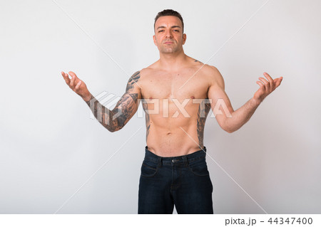 Portrait Of Shirtless Man With Tattoos Against White Background 44347400