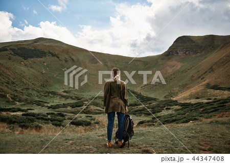 Young woman holding backpack and looking at the mountain 44347408