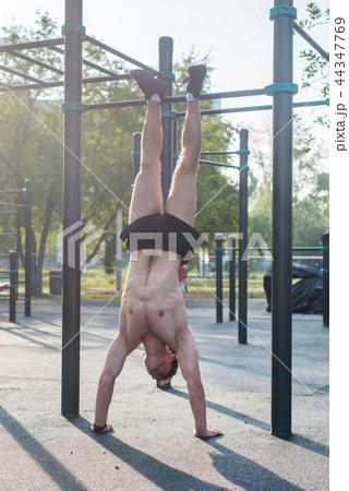 Young fit muscular man doing handstand Workout outdoors. 44347769