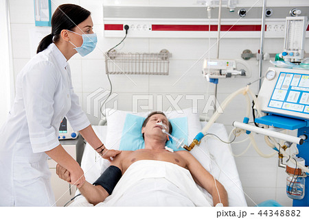 Nurse checking condition of sick middle aged man after surgery Nurse checking condition of sick middle aged man after surgery 44348882