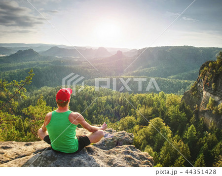 Man meditates in yoga position in mountains above Man meditates in yoga position in mountains above 44351428