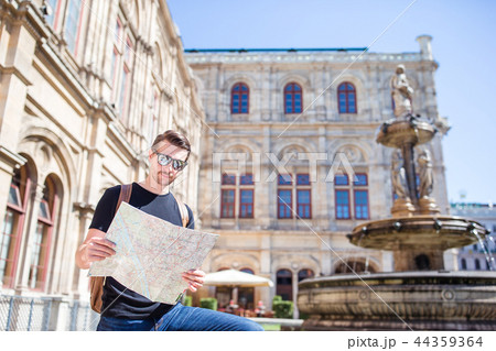 Man tourist with a city map and backpack in Europe street. Caucasian boy looking with map of Man tourist with a city map and backpack in Europe street. Caucasian boy looking with map of 44359364