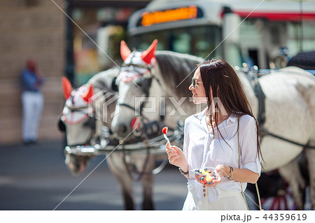 Tourist girl enjoying a stroll through Vienna and looking at the beautiful horses in the carriage Tourist girl enjoying a stroll through Vienna and looking at the beautiful horses in the carriage 44359619
