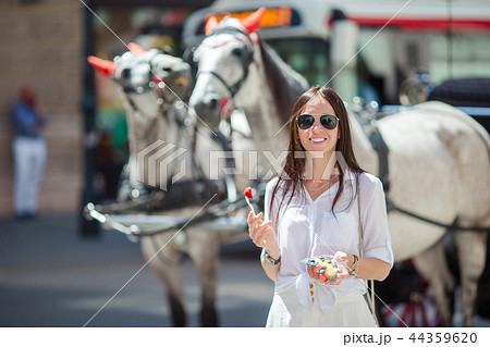 Tourist girl enjoying a stroll through Vienna and looking at the beautiful horses in the carriage Tourist girl enjoying a stroll through Vienna and looking at the beautiful horses in the carriage 44359620