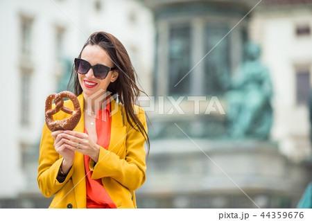 Beautiful young woman holding pretzel and relaxing in park Beautiful young woman holding pretzel and relaxing in park 44359676