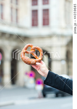 Salted pretzel in the hands of a man on background of the Vienna Opera Salted pretzel in the hands of a man on background of the Vienna Opera 44359685