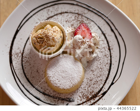 Yellow icecream with white cream and strawberry. 44365522