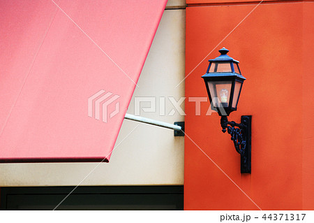 赤い壁に取り付けられた黒いアンティーク調の外灯 44371317