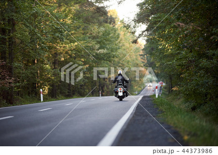 Biker in black leather outfit driving modern powerful motorcycle along sunny road on summer day. Biker in black leather outfit driving modern powerful motorcycle along sunny road on summer day. 44373986