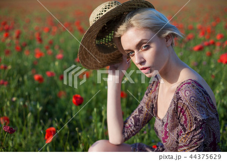 a woman farmer in a field of red poppies 44375629