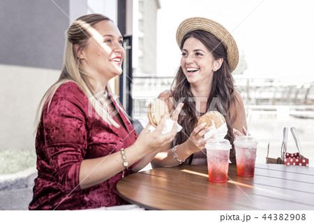 Delighted joyful plump women enjoying fast food Delighted joyful plump women enjoying fast food 44382908
