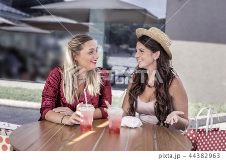 Happy delighted women sitting together at the table Happy delighted women sitting together at the table 44382963