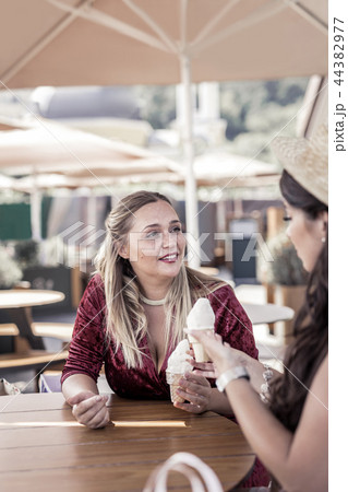 Pleasant nice woman offering an ice cream cone to her friend Pleasant nice woman offering an ice cream cone to her friend 44382977