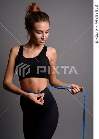 Young beautiful woman ready for gym against gray background 44383853