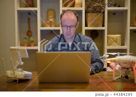 Mature man with drone and laptop in the dining room at home Mature man with drone and laptop in the dining room at home 44384295