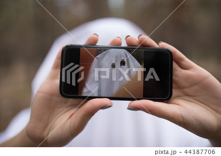 Woman in halloween ghost costume make selfie in the forest. Woman in halloween ghost costume make selfie in the forest. 44387706